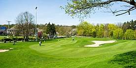 Golfplatz an einem sonnigen Tag Grüner Golfplatz mit Spielern und Bunkern unter blauem Himmel.