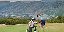 Golfunterricht auf dem Grün Ein Trainer zeigt einem jungen Mädchen die richtige Golftechnik.